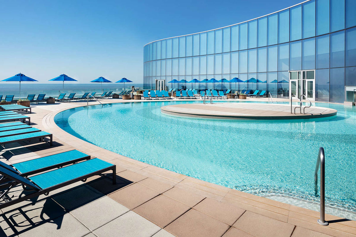 Ocean Casino Resort Outdoor Pool Deck with Blue Sky and Lounge Chairs and Umbrellas in an empty pool setting (with no people).